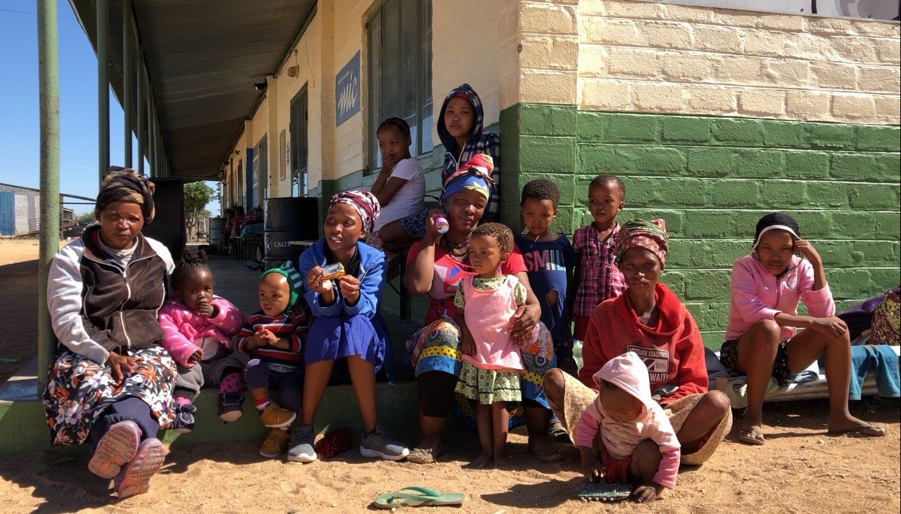 Parents and children sitting outside a building looking into the camera