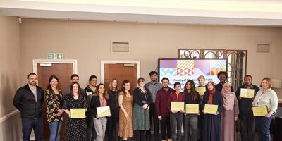 Staff and students lining up with their award certificates smiling at the camera