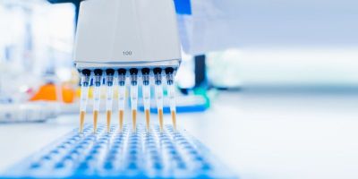 A row of eight thin pipettes attached to a machine injecting fluid into a tray.