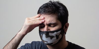 Man with headache wearing face mask