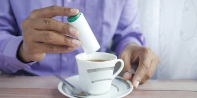 Someone putting sweeteners in a hot drink.
