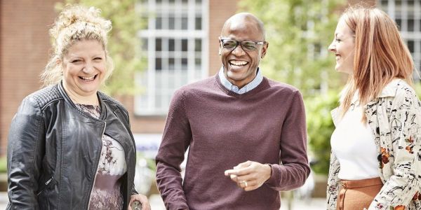 Two women and a man standing together smiling