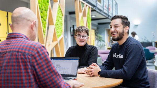 Two School of Healthcare students speak with a tutor in the Baines Wing lounge