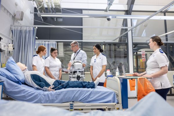 Adult nursing students listen to a tutor in the clinical skills suite