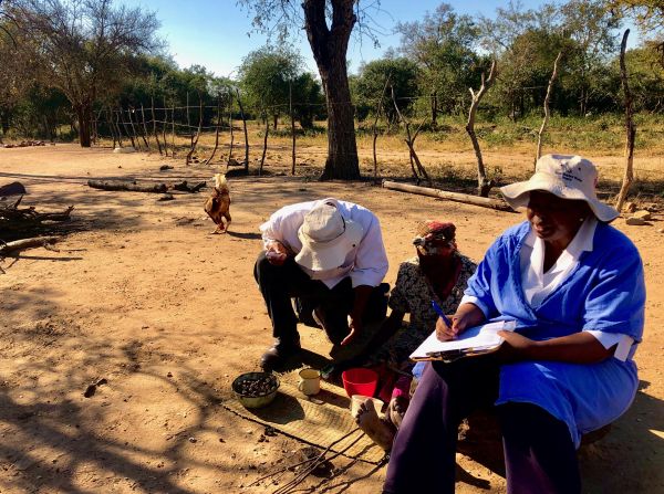 A nurse writing down information sitting on the floor outside