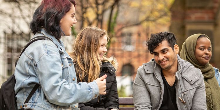 Group of students sat on a campus bench