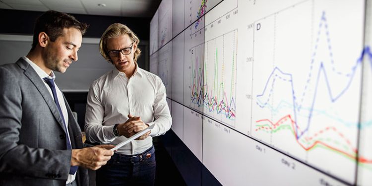 Academics looking at research and innovation data on a screen representing research at the School of Psychology at the University of Leeds