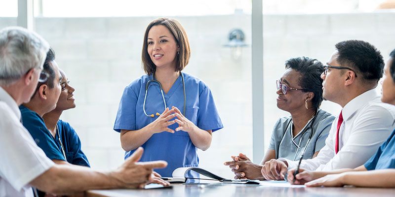 medical professionals sat around a table 
 talking about research into EDUCATING DOCTORS TO PROVIDE SAFER CARE