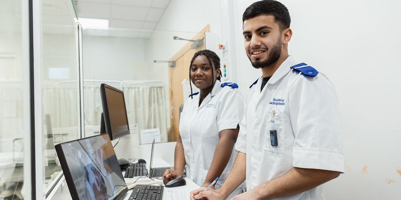 Two Radiography students smiling looking at an X-ray